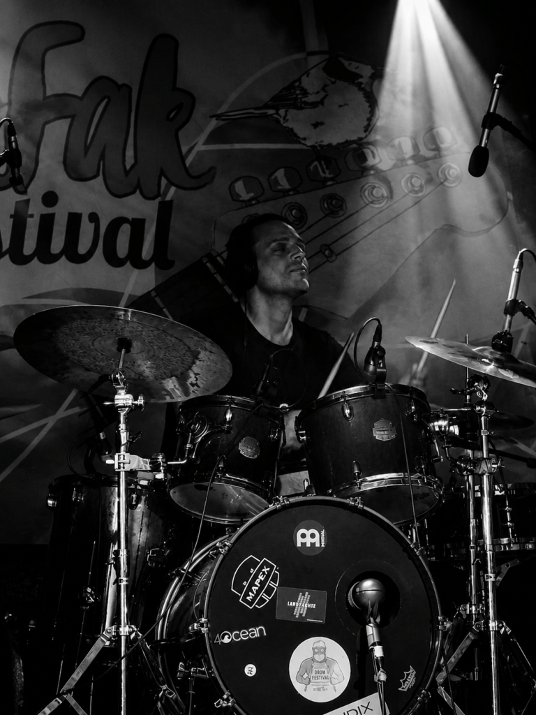 marco rogowski spielt am Live Drumset schaut stolz nach oben im Scheinwerfer licht